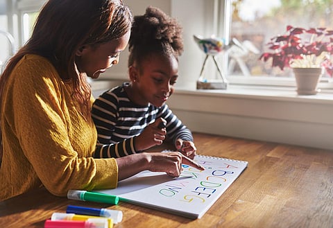 Mujer y niño aprendiendo el alfabeto en casa, madre e hija negras