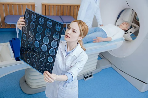 At the CT laboratory. Beautiful experienced female radiologist looking at the MRI scan images and putting a diagnosis while standing in the CT lab