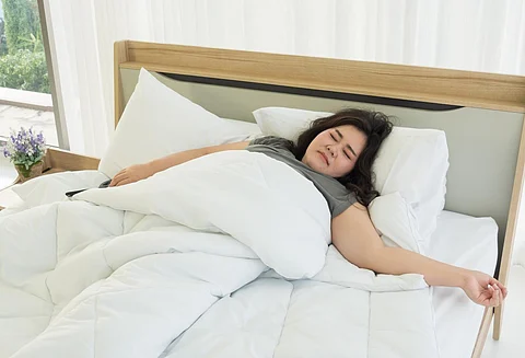 An Asian woman is sleeping in a comfortable bed.