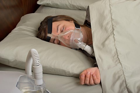 Mujer usando máquina CPAP para apnea del sueño