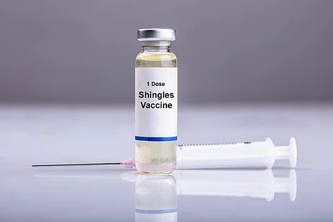 Close-up Of Shingles Vaccine And Syringe On Reflective Desk