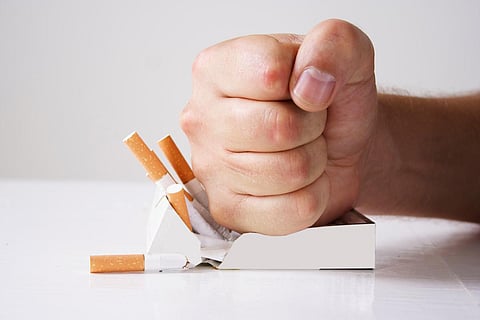 Hand crushing cigarettes over white background