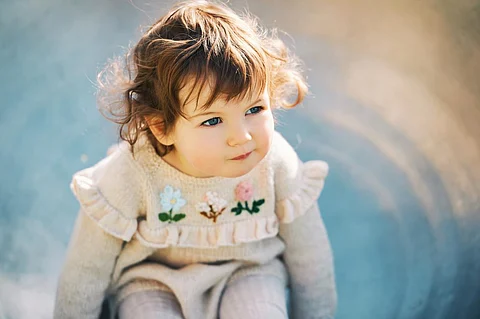 Outdoor close up portrait of adorable toddler girl having fun on playground, 1 - 2 year old kid playing in park