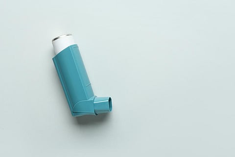 Modern asthma inhaler on grey background