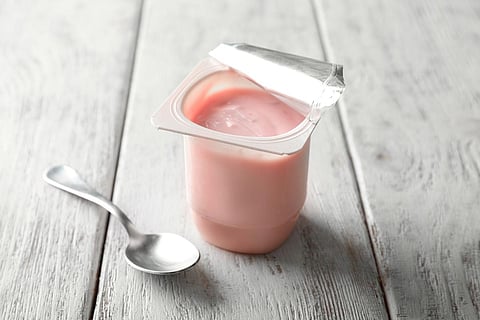 Plastic cup with yummy strawberry yogurt on wooden background