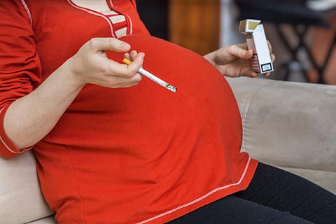 Fumar durante el embarazo. Mala madre embarazada sostiene un cigarrillo en la mano.