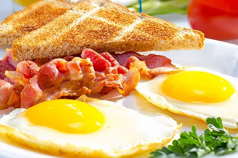 Tocino con huevos soleados servidos con tostadas.