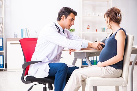 Médico joven que controla la presión arterial de una mujer embarazada