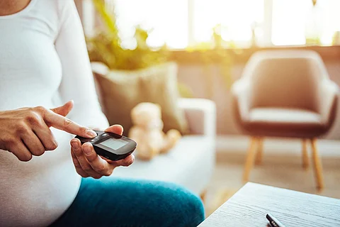 Concepto de embarazo, salud y glucemia: mujer hermosa embarazada que verifica el nivel de azúcar en la sangre con glucómetro y dispositivo de punción en casa