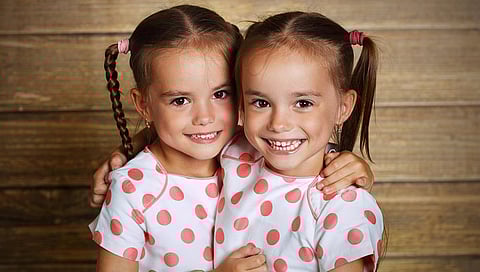 happy family children twin sisters hugging and laughing