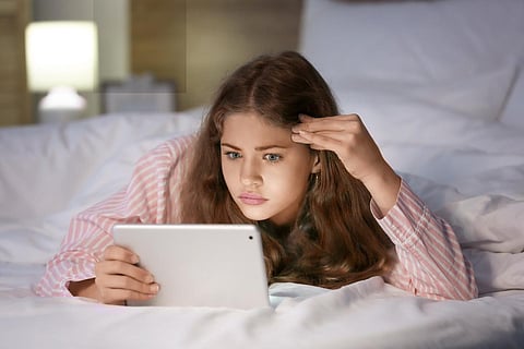 Adolescente emocional con tableta en la cama por la noche