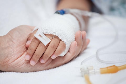 Adulto sosteniendo la mano de un niño que tiene una vía intravenosa