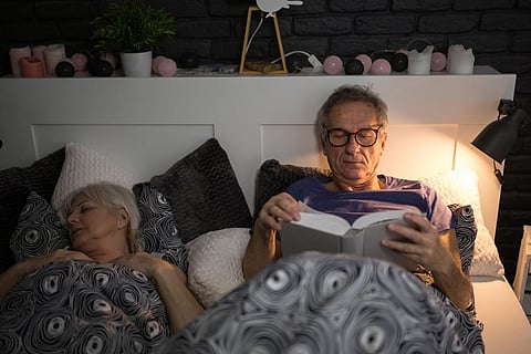 Hombre mayor leyendo un libro en la cama antes de dormir