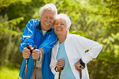 Pareja de personas mayores haciendo marcha nórdica en un día soleado de verano