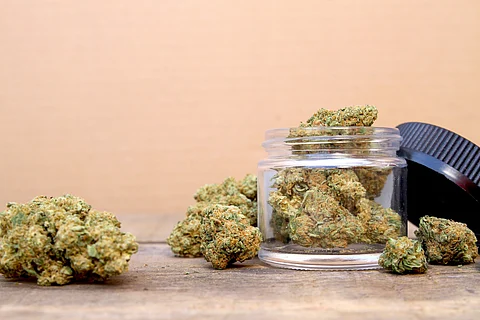 Photo of marijuana in a clear glass jar on a wood table