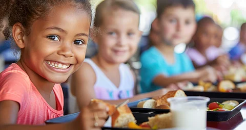 Niños almorzando en la escuela con una taza de leche
