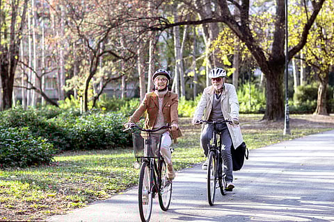 Pareja mayor con bicicletas y cascos en el parque