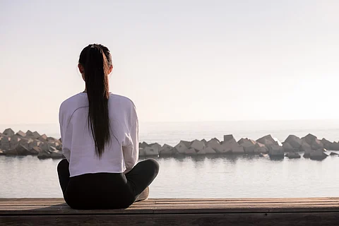 Vista trasera de una mujer joven sentada meditando