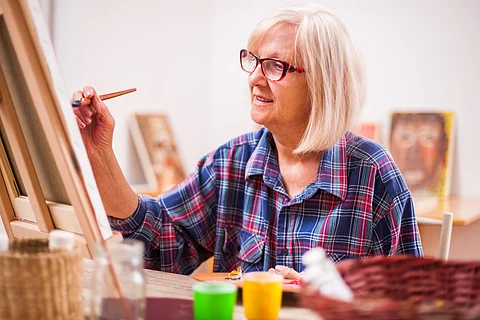 Una anciana está pintando en su casa. Pasatiempo de jubilación.