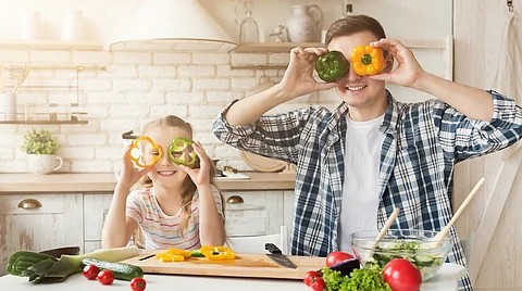 Padre feliz y su hija divirtiéndose en la cocina