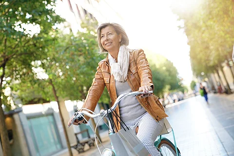 Mujer mayor montando bicicleta de ciudad en la ciudad