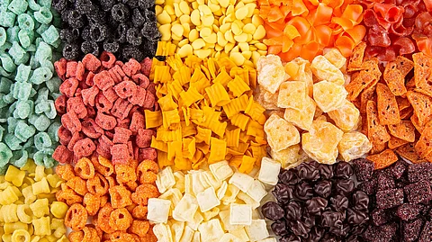 Coloridos alimentos procesados dispuestos sobre una superficie blanca, que muestran los hábitos dietéticos modernos y el impacto de la conveniencia en la nutrición y las opciones de estilo de vida.