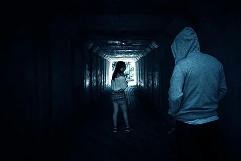 Problemas sociales, hermosa mujer al teléfono mientras camina por el túnel y es acosada por un extraño