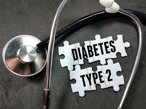 Concepto médico. Texto DIABETES TIPO 2 en rompecabezas con estetoscopio sobre fondo negro.