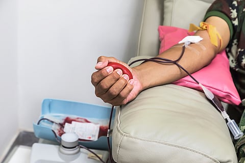 Donante de sangre en la donación con pelota roja que rebota en la mano.