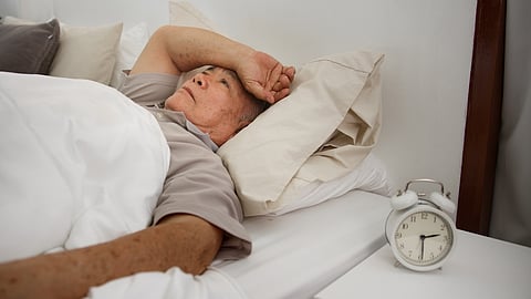 Un hombre mayor asiático tiene insomnio o insomnio en la cama de su casa debido al estrés, el nerviosismo y la preocupación