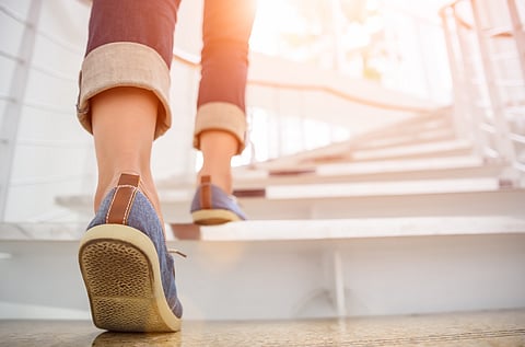 Mujer adulta joven subiendo las escaleras con fondo de deporte solar.