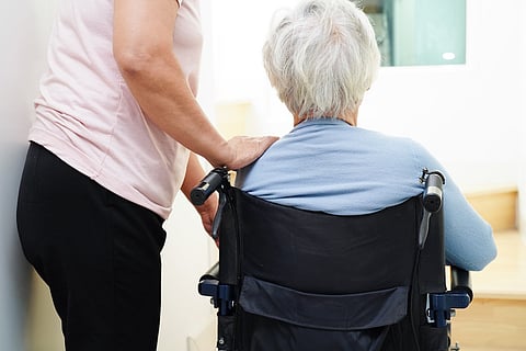 Mujer asiática mayor en silla de ruedas con cuidador ayuda para bajar las escaleras y prevenir accidentes, resbalones y caídas en casa.