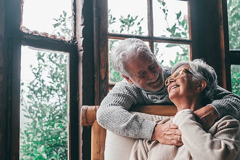Retrato de una pareja de dos ancianos felices y sanos, sonriendo y mirándose el uno al otro. Primer plano de abuelos maduros disfrutando y divirtiéndose juntos en casa, en interior.