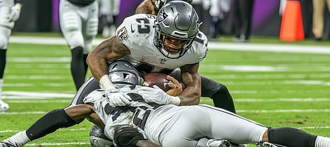 Placaje de contacto total en fútbol americano por un jugador de la NFL con el balón fuerte agarrado bajo el brazo