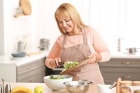 Mujer madura y hermosa cocinando en la cocina
