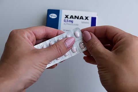 Mujer que toma pastillas de Xanax de Pfizer para tratar trastorno de pánico y ansiedad. Paquete de pastillas. Concepto de farmacia y medicamento.