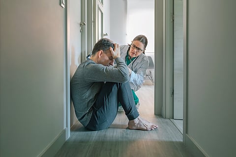 Psiquiatra tranquilizadora y ayudando con empatía hacia un paciente masculino sentado en la sala del centro de salud mental