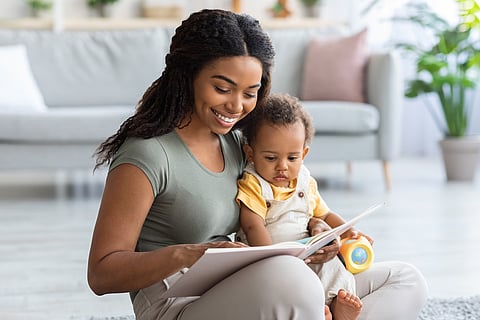 Libro de lectura de mamá afroamericana cariñosa para su hijo pequeño en casa