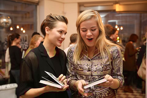 Ronja Salmi ja valokuvaaja Emmi Kähkönen (oik.) tutkivat painotuoretta uutuuskirjaa keskiviikkona Helsingin Kalliossa järjestetyssä julkistamistilaisuudessa.