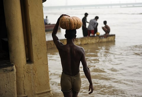 An Indian man carries a pumpkin he salvaged from the rising waters of the Yamuna river in New Delhi on June 18, 2013. PHOTO CREDIT: MANAN VATSYAYANA