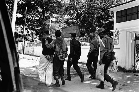 A handcuffed man is led away by police and an intelligence officer, U Wi Za Ya road. Rangoon, March 2005. Photo: Nic Dunlop
