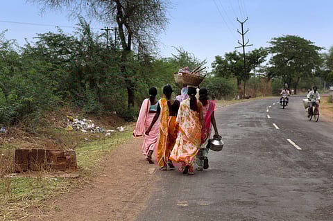 A group of women carry baskets with tools on their heads as they walk along the road in Chandrapur, Maharashtra. Photo: NurPhoto / IMAGO