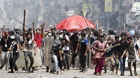 Protesters outside the headquarters of Bangladesh’s state broadcaster, which was set alight after police fired rubber bullets at them.