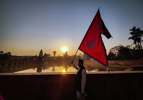 A man carries the national flag during the first sunrise of Nepali New Year in Kathmandu in 2023. (This featured image was added online in 2024, and did not appear in the original print publication.)