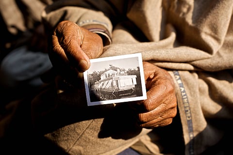 A close up image of a resident of Srinagar holding a black-and-white photograph of his grandfather on his houseboat