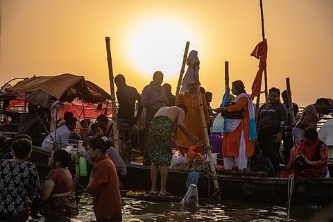 People bathing at the river against a sunset backdrop.