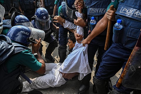 Ten or more Bangladesh police officers drag a protester across the streets of Dhaka by force.
