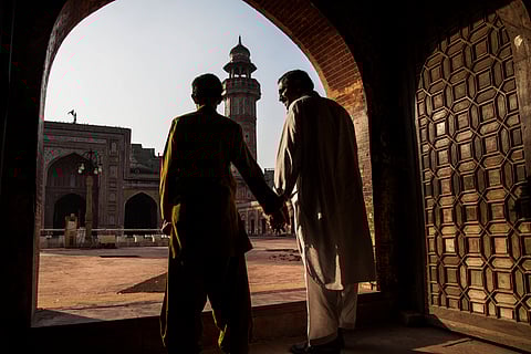 An image of a father and son hand-in-hand inside the Wazir Khan mosque complex in Lahore.