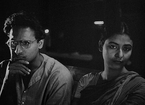 Black and white film still of a man and woman next to each other.