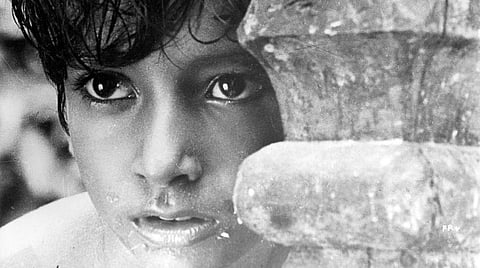 Film still of a child looking past a post.